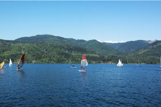 Sailboats dot Lake Whatcom surface in bright colors in front of Lakewood
