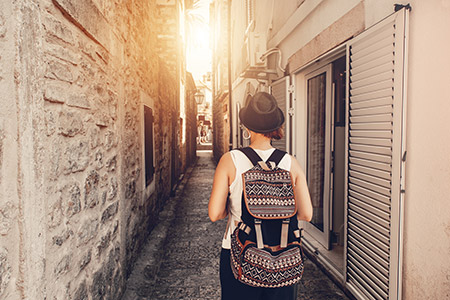 A individual with a backpack strolling through a narrow alleyway, exploring the hidden paths of the city.