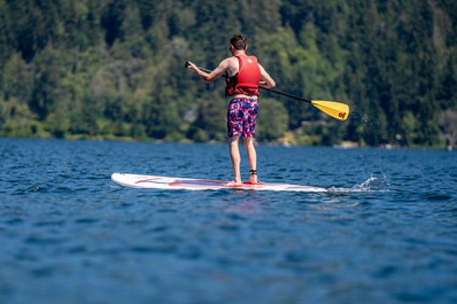 An individual gracefully paddleboarding on calm water.